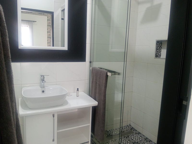 Modern bathroom featuring a vessel sink vanity, glass-enclosed shower with a decorative niche, and stylish patterned floor tiling.
