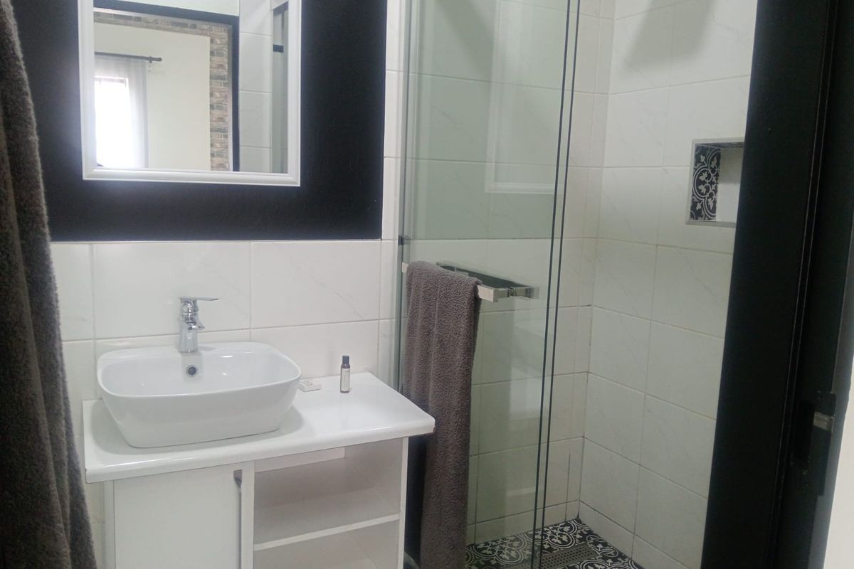 Modern bathroom featuring a vessel sink vanity, glass-enclosed shower with a decorative niche, and stylish patterned floor tiling.