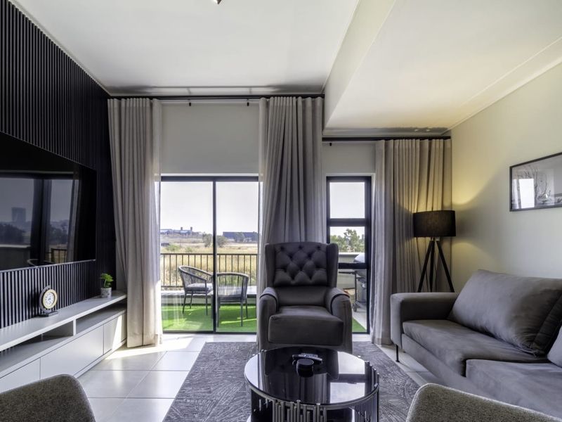 Modern living room featuring a stylish slatted feature wall, tiled flooring, and large sliding glass doors providing natural light and access to the balcony.