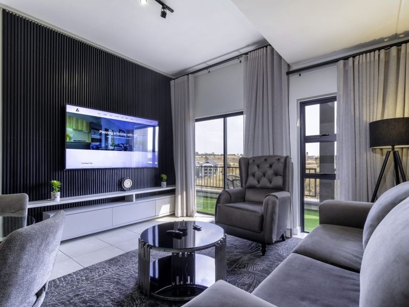 Modern living room featuring a stylish black slatted feature wall, built-in media console, and large sliding glass doors leading to a balcony.