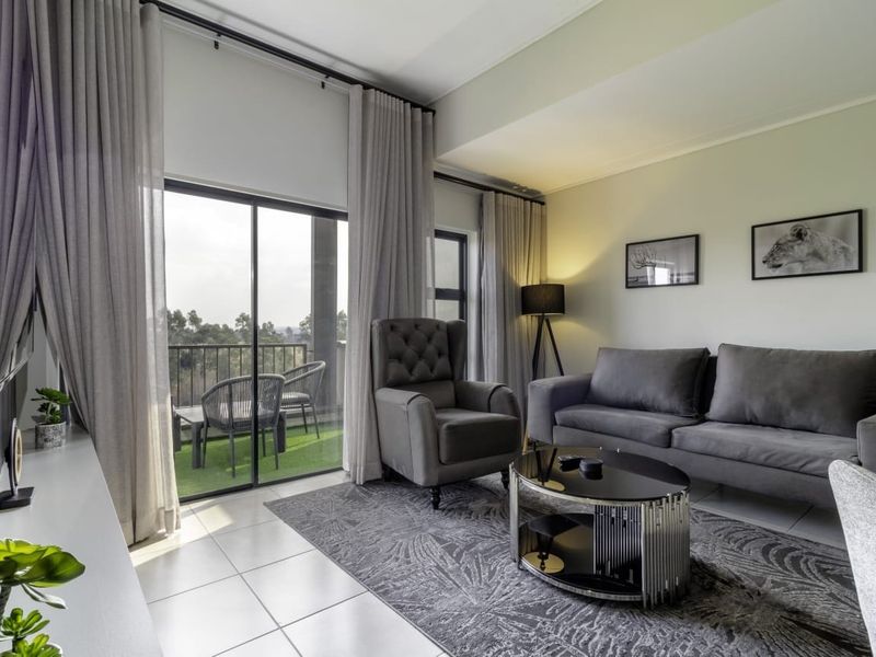 A well-maintained living room featuring tiled flooring and large sliding glass doors that provide access to a private balcony.