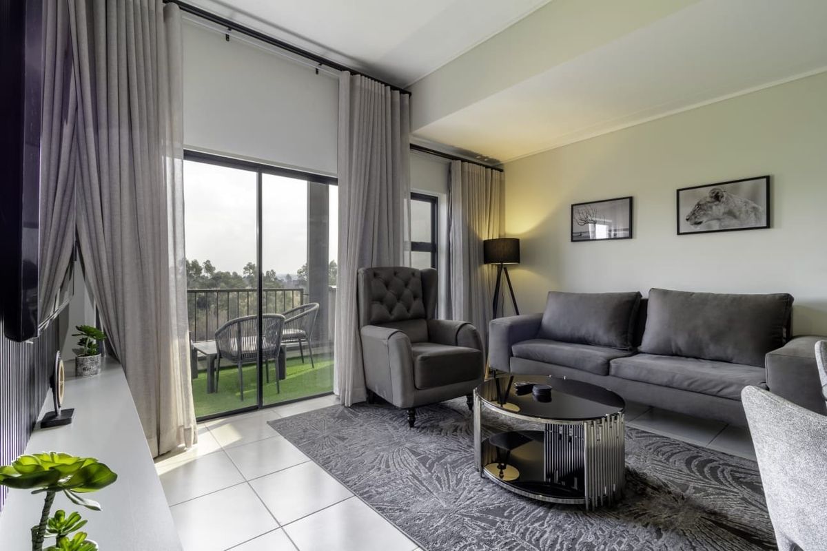 A well-maintained living room featuring tiled flooring and large sliding glass doors that provide access to a private balcony.