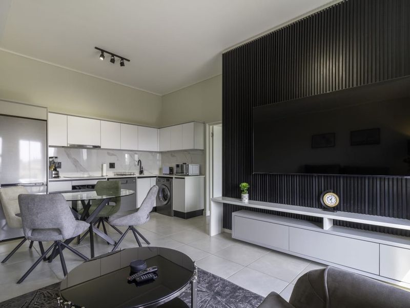 Modern open-plan living area featuring a sleek kitchen with built-in cabinetry and a striking black slatted feature wall with integrated media storage.