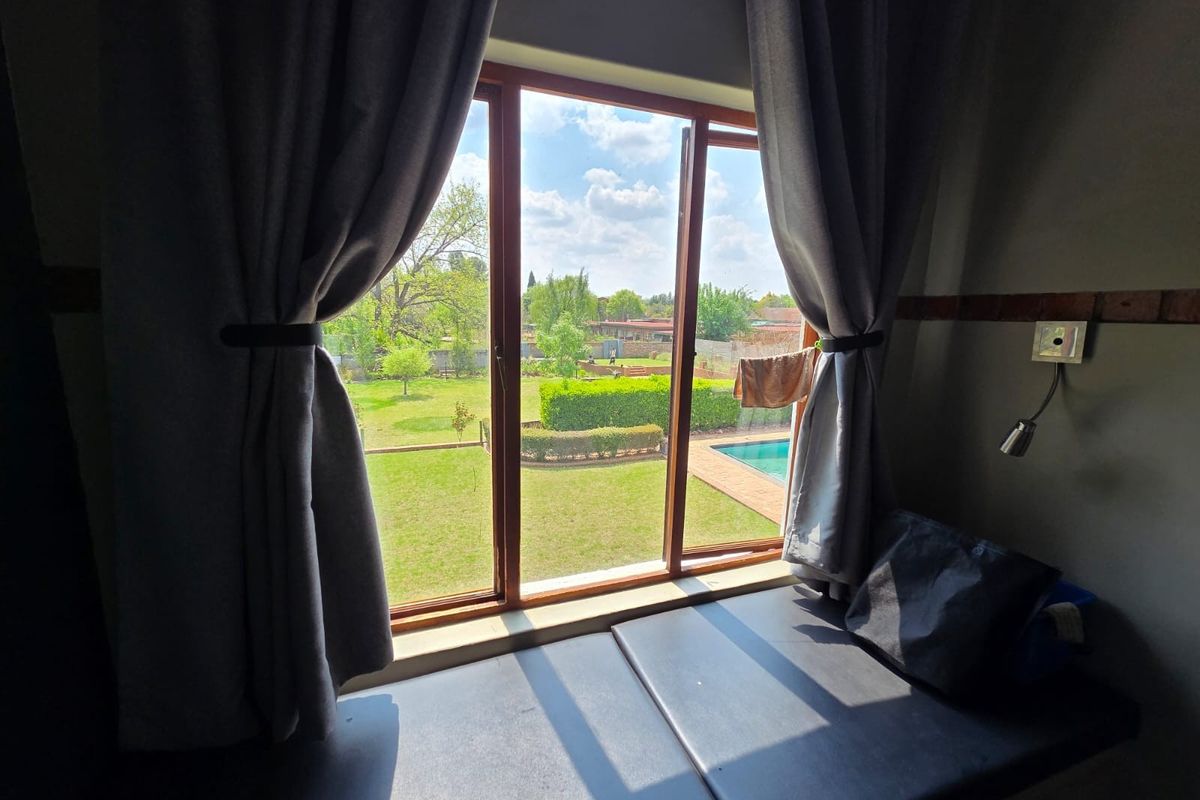 A bedroom featuring a built-in window seat with views overlooking the garden and swimming pool area.