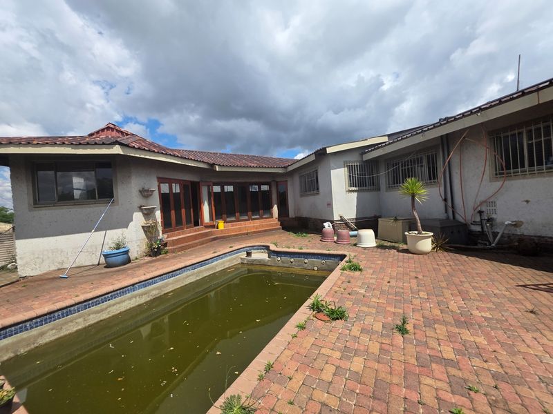 Rear exterior view featuring a swimming pool with paved surround and direct access to the house via sliding doors.