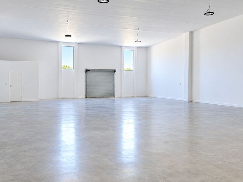 Spacious open-plan commercial unit featuring polished concrete floors, high ceilings, recessed lighting, and a secure roller shutter door.