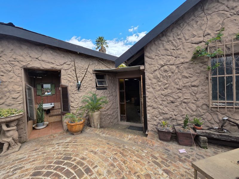 A rear courtyard featuring textured stone-clad walls, brick paving, and an external wash basin area.