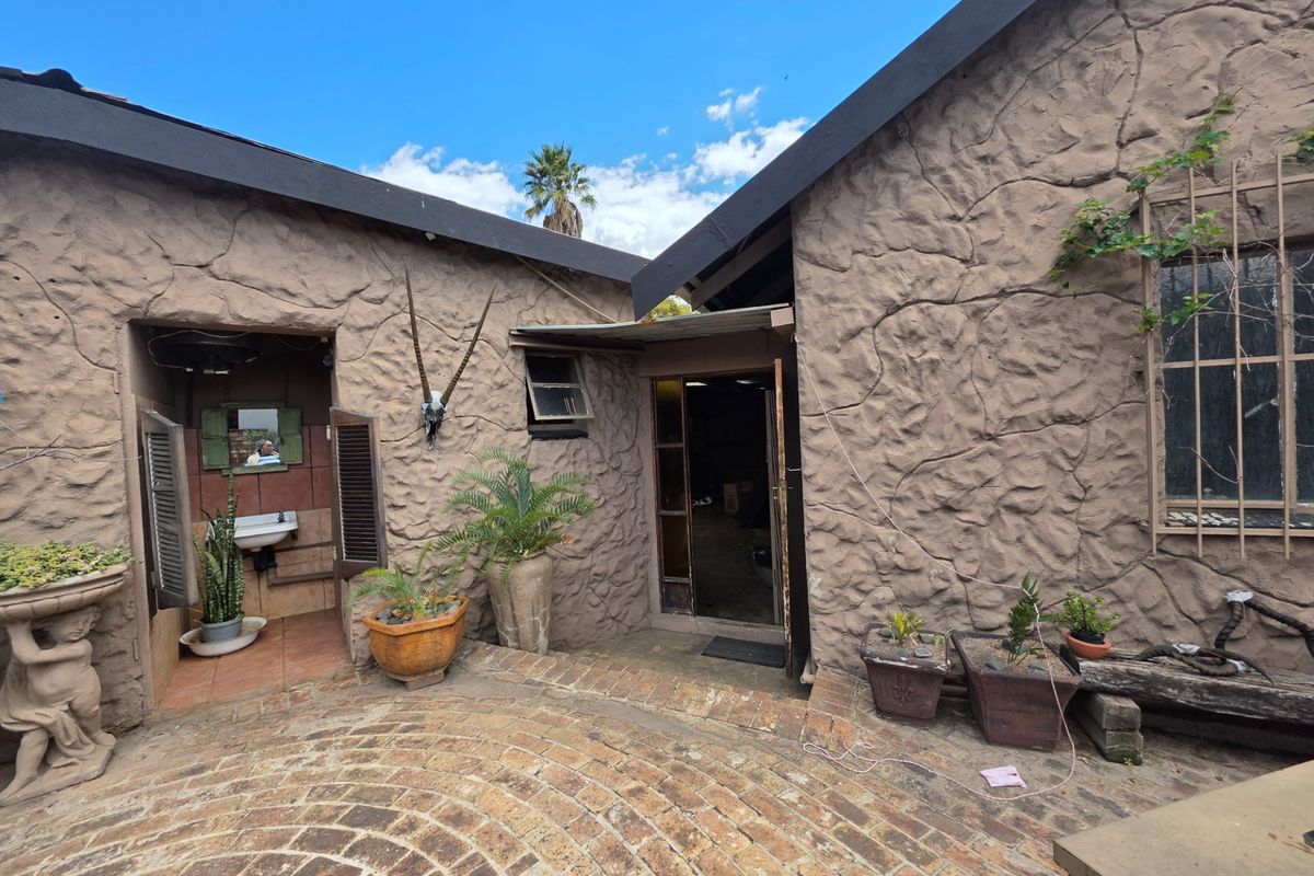 A rear courtyard featuring textured stone-clad walls, brick paving, and an external wash basin area.