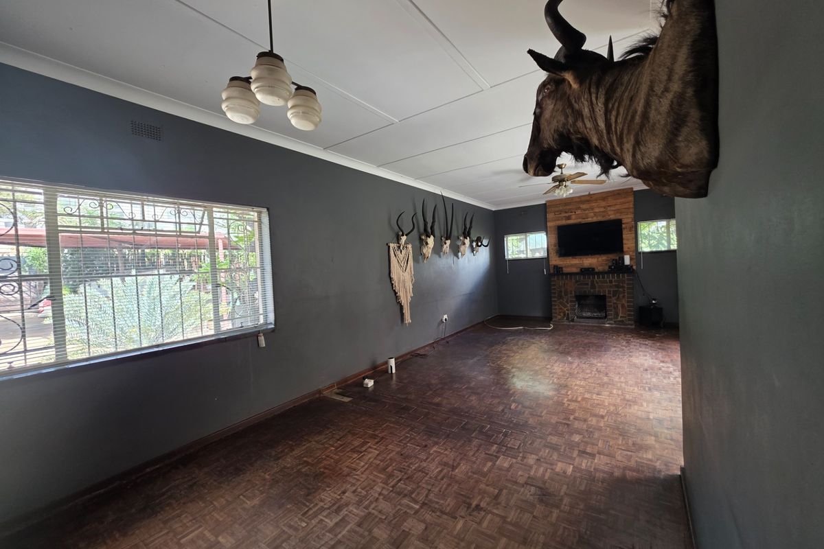 Spacious living room featuring a brick fireplace, parquet flooring, and security bars on the windows.