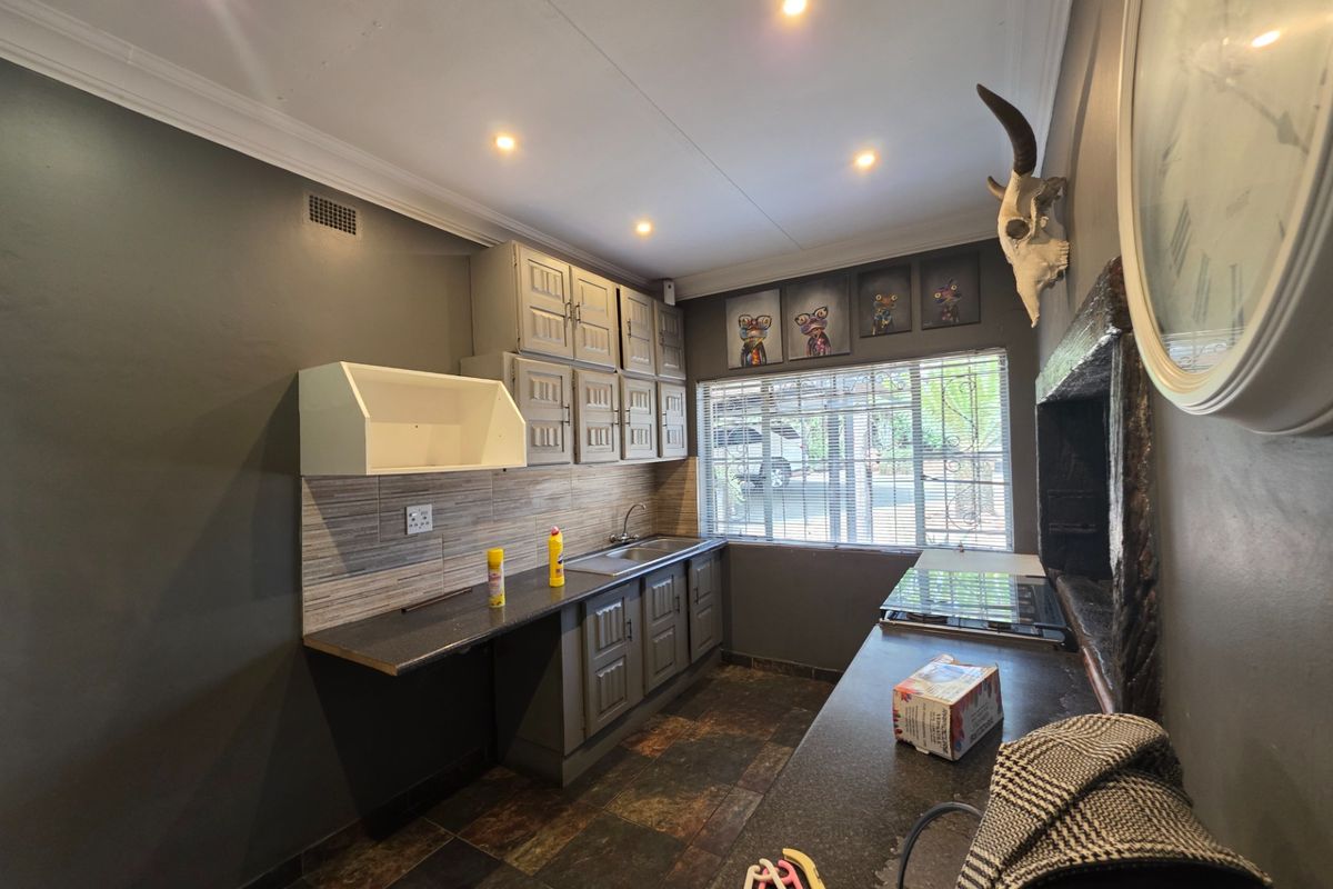 Compact kitchen featuring dark cabinetry, tiled flooring, a built-in hob, and a stainless steel sink with a tiled backsplash.