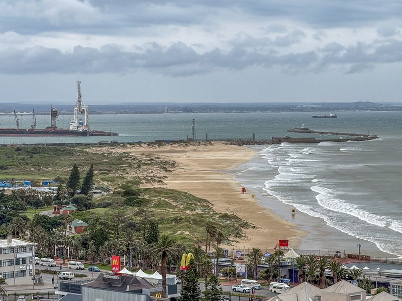 Elevated coastal view overlooking the beach, harbour entrance, and surrounding urban landscape.