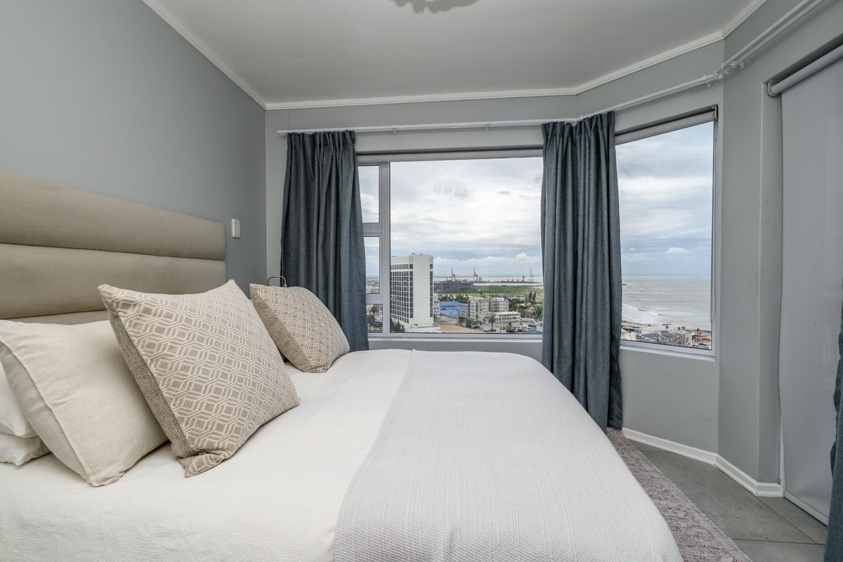A well-maintained bedroom featuring a large bay window with expansive coastal and city views.
