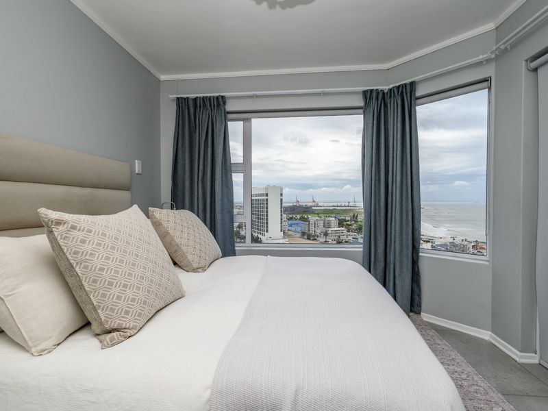 A well-maintained bedroom featuring a large bay window with expansive coastal and city views.