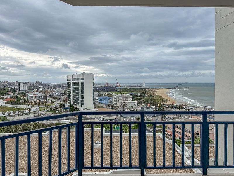 A balcony offering expansive coastal and city views, featuring a secure metal balustrade and tiled flooring.