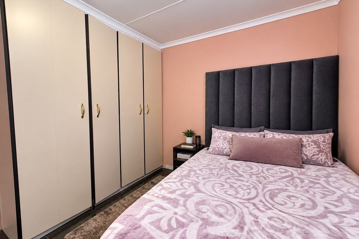 A well-maintained bedroom featuring floor-to-ceiling built-in cupboards and a coved ceiling, providing ample storage and a clean, finished aesthetic.