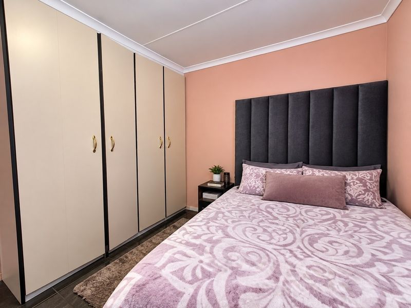 A well-maintained bedroom featuring floor-to-ceiling built-in cupboards and a coved ceiling, providing ample storage and a clean, finished aesthetic.