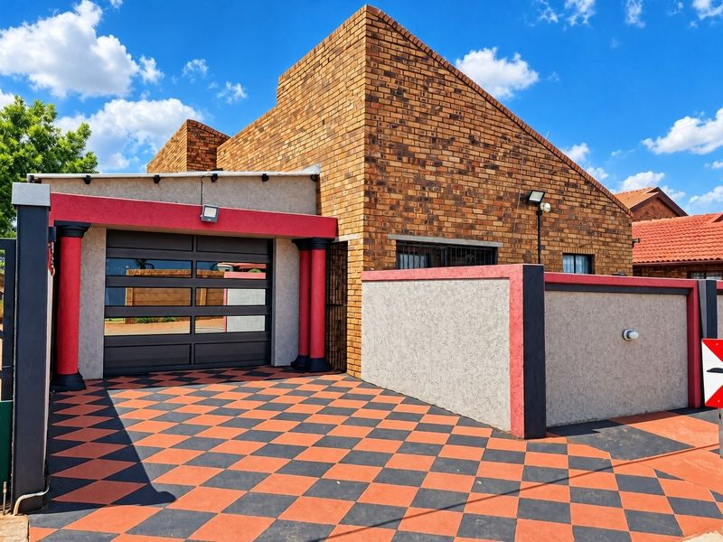 Front elevation of a house featuring a face brick facade, a distinctive checkered paved driveway, and a secure garage entrance.