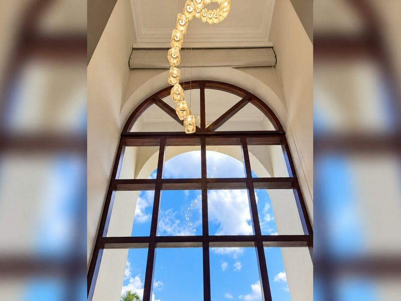 A grand entrance featuring a large arched timber-framed window and an elegant decorative pendant light fixture.