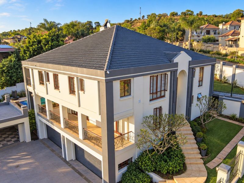 Aerial view of a modern multi-story residential property featuring a tiled roof, double garage, spacious balconies with iron railings, and a well-maintained garden.