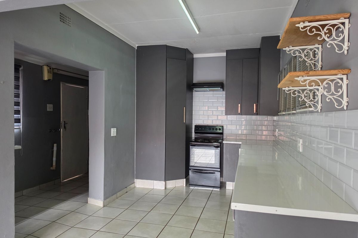 A functional kitchen featuring dark grey cabinetry, white subway tile backsplash, and tiled flooring, offering a clean and neutral space ready for personalization.