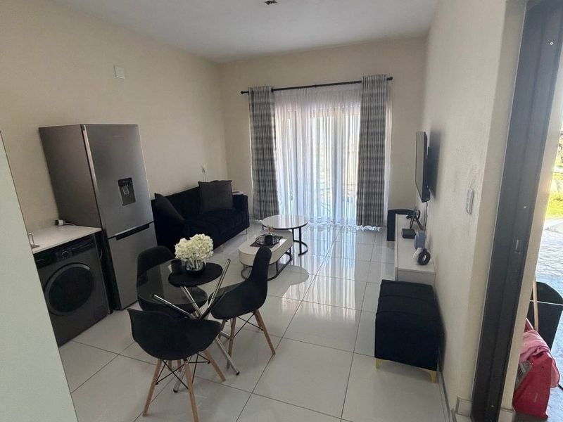 An open-plan living and dining area featuring large format floor tiles, a sliding door to the exterior, and integrated laundry plumbing.