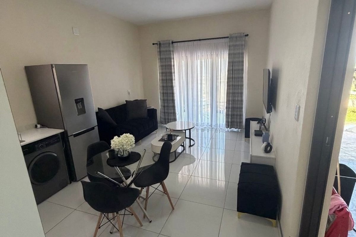 An open-plan living and dining area featuring large format floor tiles, a sliding door to the exterior, and integrated laundry plumbing.