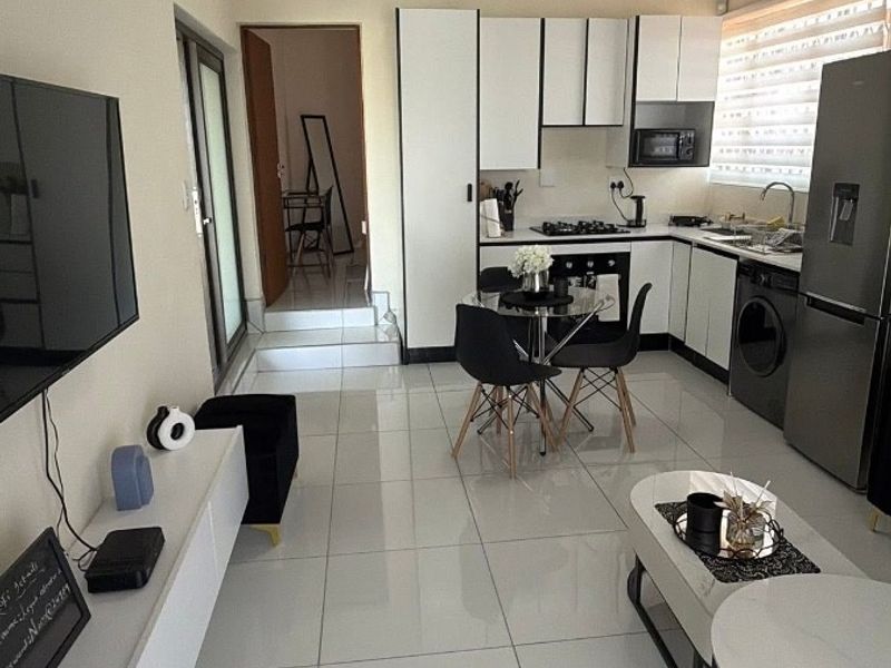Modern open-plan living area featuring a sleek kitchen with built-in cabinetry, gas hob, and tiled flooring throughout, creating a bright and functional space.