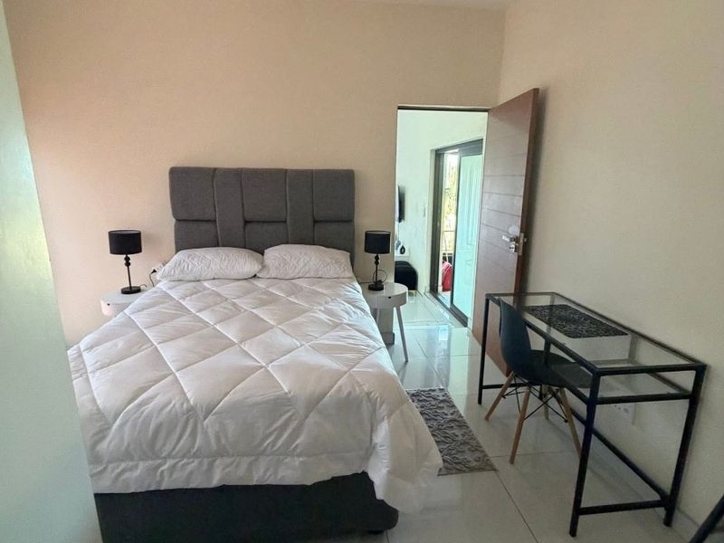 A well-maintained bedroom featuring neutral walls, tiled flooring, and direct access to an adjoining space.