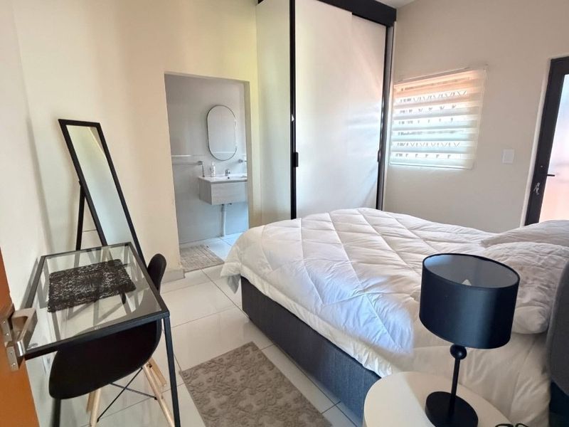 A well-maintained bedroom featuring tiled flooring, a built-in wardrobe, and an adjoining en-suite bathroom with modern fixtures.