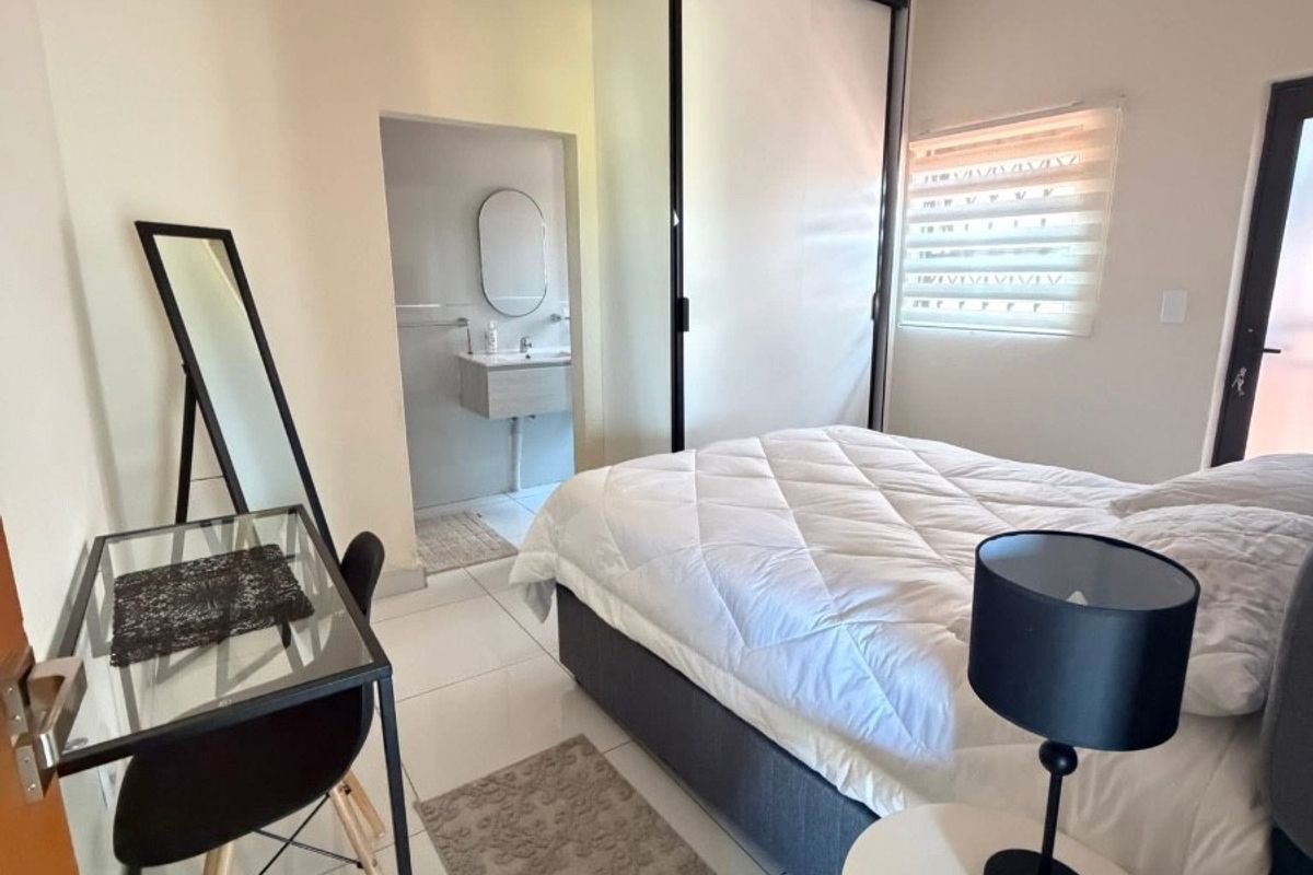 A well-maintained bedroom featuring tiled flooring, a built-in wardrobe, and an adjoining en-suite bathroom with modern fixtures.