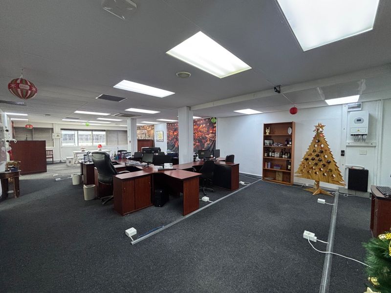 Spacious open-plan office area featuring recessed lighting, carpeted flooring, and integrated electrical trunking, suitable for a professional workspace environment.