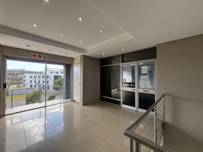 A bright and modern office lobby or waiting area featuring tiled floors, recessed lighting, and a glass-partitioned entrance to the office suite.