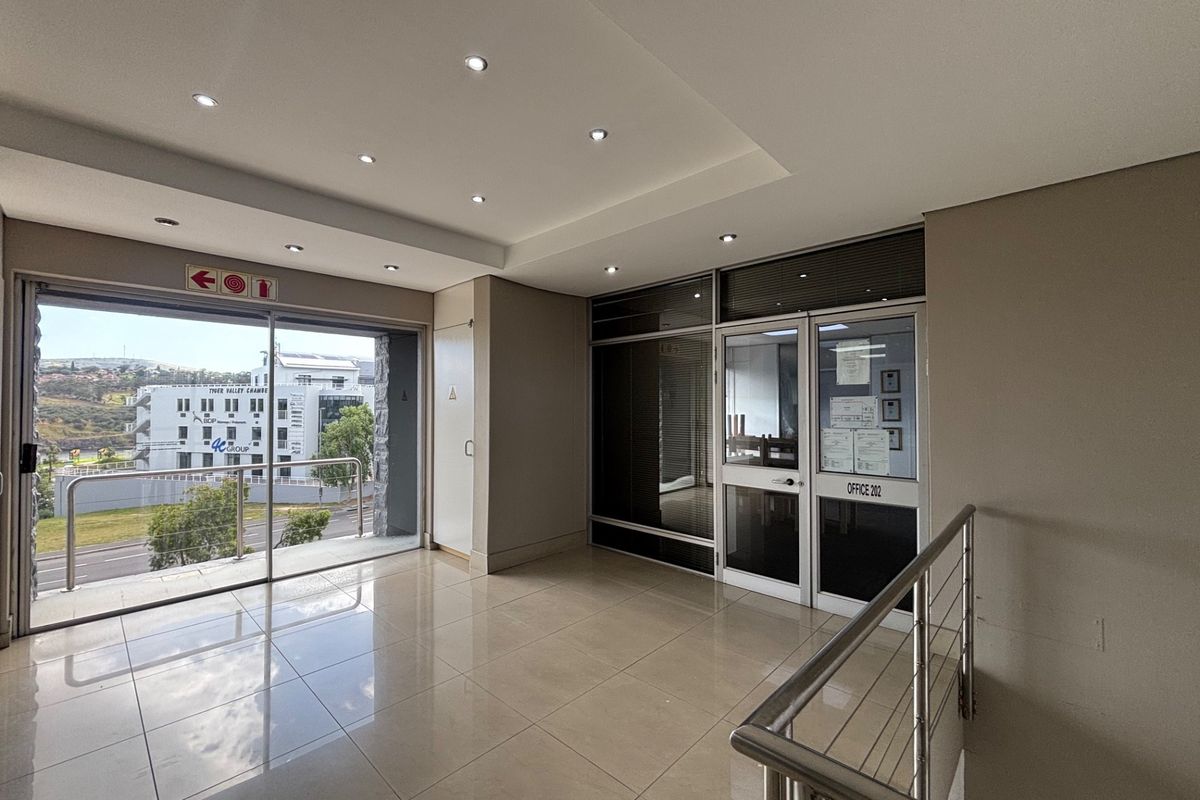 A bright and modern office lobby or waiting area featuring tiled floors, recessed lighting, and a glass-partitioned entrance to the office suite.