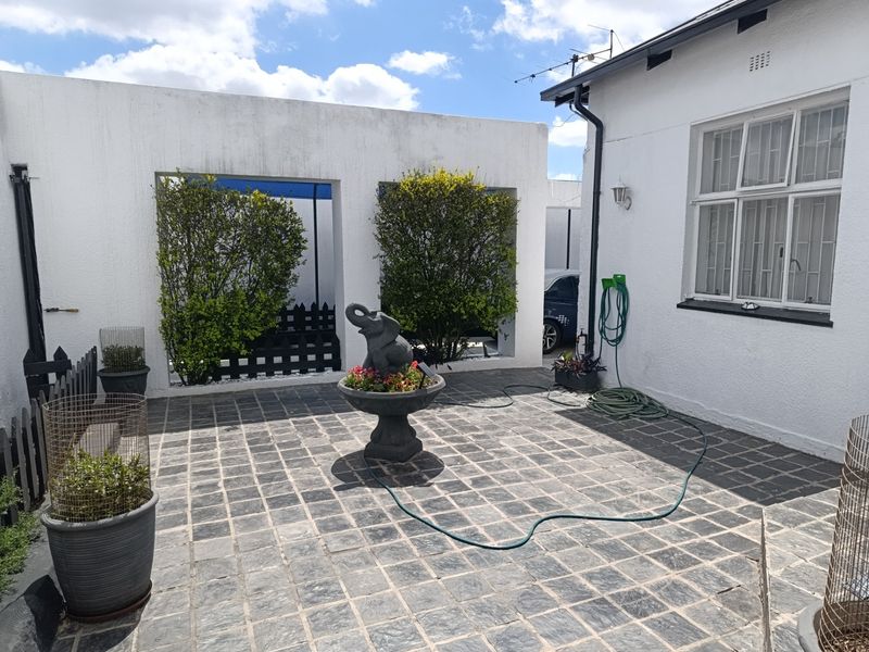 A paved rear courtyard area featuring stone tiling, security-barred windows, and a central decorative feature, providing a functional outdoor space.