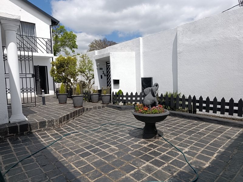 A well-maintained front courtyard featuring stone paving, a boundary wall, and a balcony, providing a secure and private entrance area.