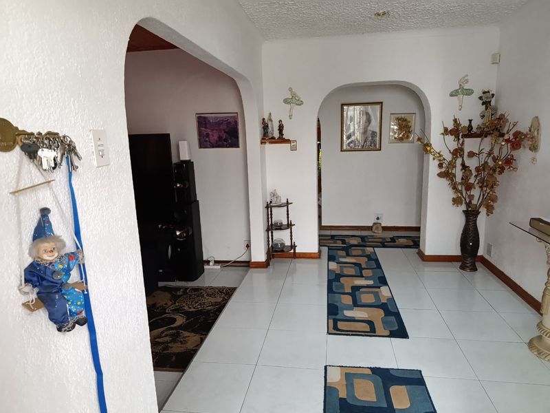 A living area featuring distinctive arched doorways, white walls, and tiled flooring, providing a neutral foundation for potential interior updates.