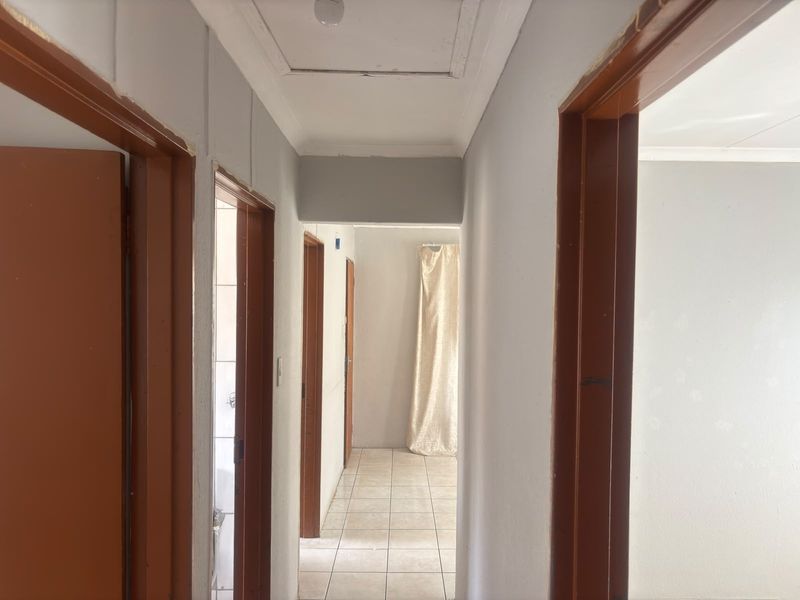 A functional hallway featuring tiled flooring and wooden door frames, providing access to multiple rooms within the property.