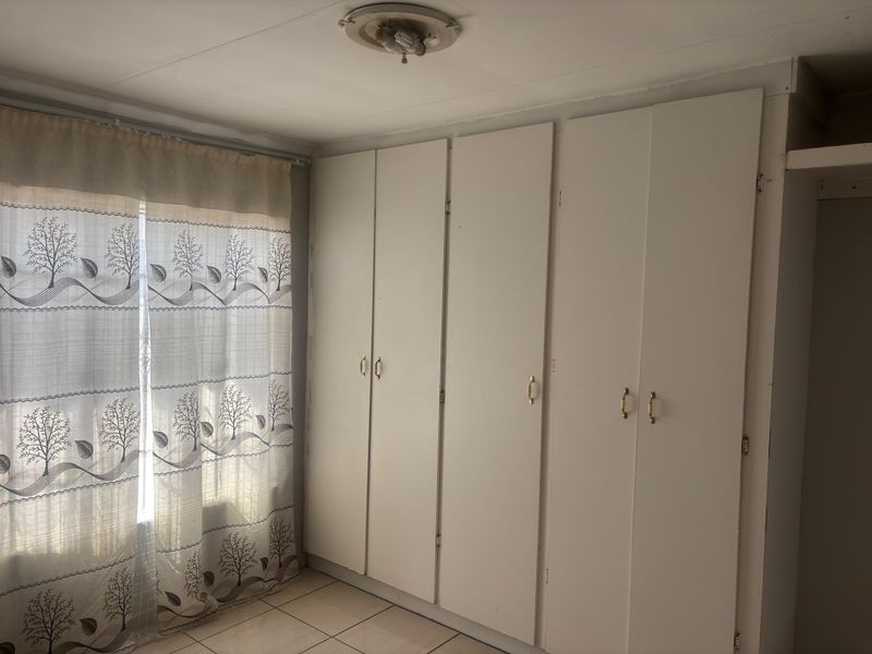 A bedroom featuring built-in cupboards and tiled flooring, offering a functional space ready for personalization.