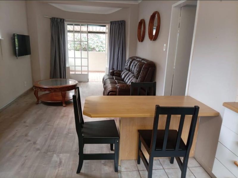 Open plan living and dining area featuring a mix of laminate and tiled flooring with direct access to an outdoor balcony.