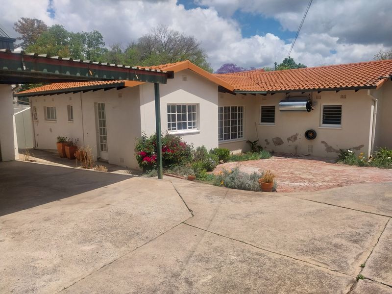 Rear exterior view of the property featuring a brick paved patio, concrete driveway, carport, and solar water heating system.