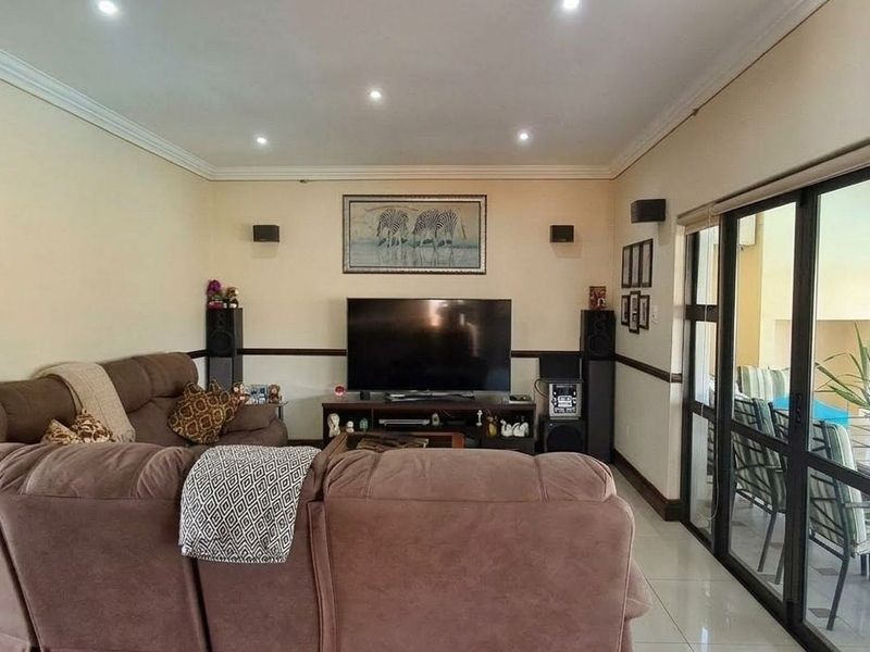 Spacious living room featuring tiled flooring, recessed lighting, and large sliding glass doors that provide seamless access to the outdoor patio area.