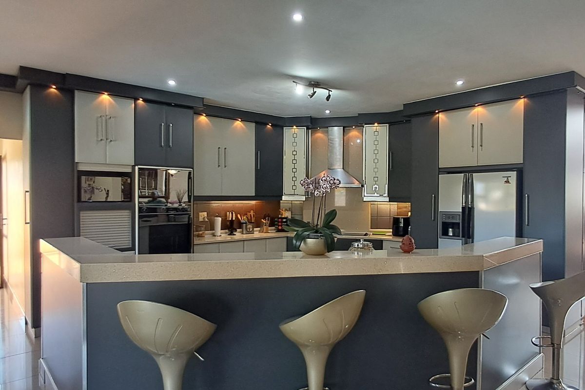 Modern kitchen featuring two-tone cabinetry, stone countertops, a breakfast bar, and integrated stainless steel appliances with recessed lighting.