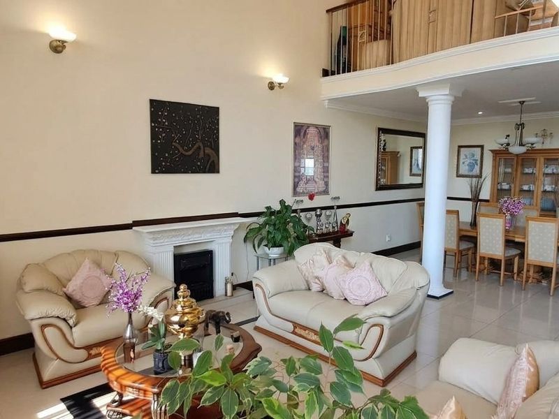 Spacious open-plan living and dining area featuring a fireplace, double-volume ceilings, and a mezzanine level overlooking the main living space.