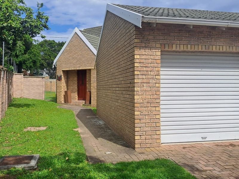 Front view of the townhouse featuring a face brick facade, a single roller garage door, and a paved driveway leading to the entrance.