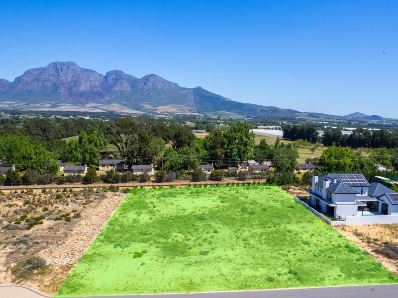 Aerial view of a vacant residential plot featuring clear boundaries and scenic mountain views in a quiet estate setting.