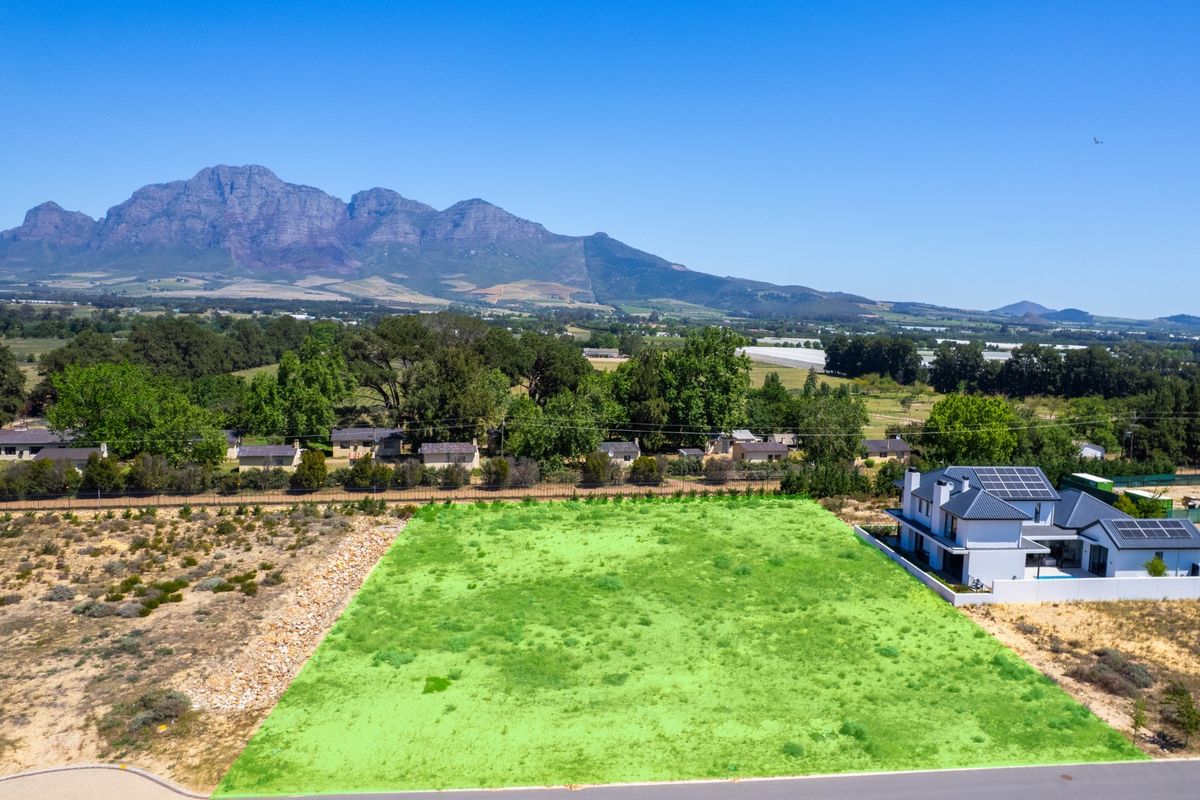 Aerial view of a vacant residential plot featuring clear boundaries and scenic mountain views in a quiet estate setting.