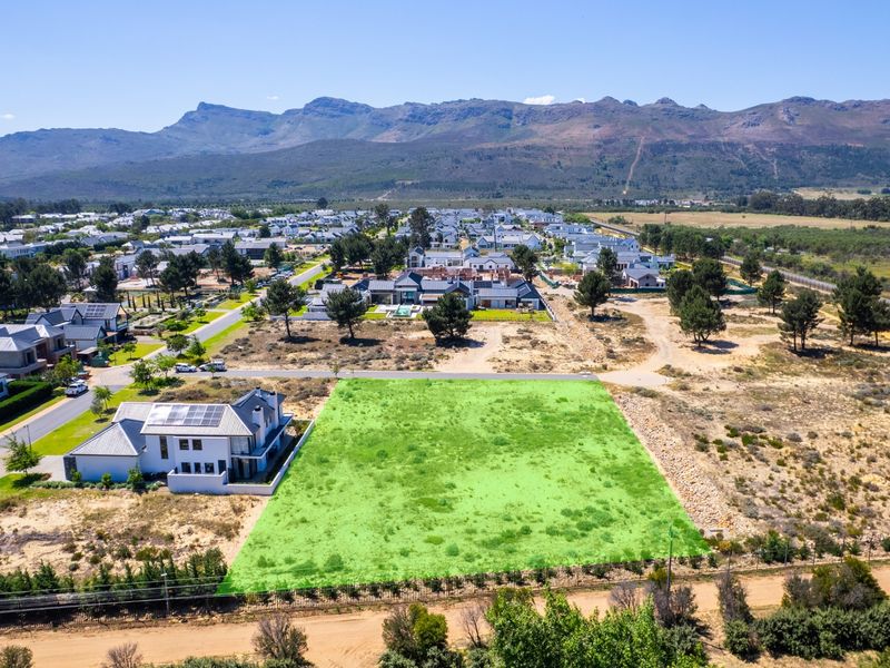 Aerial view of a vacant residential plot in a developed estate, featuring clear boundaries and mountain views.