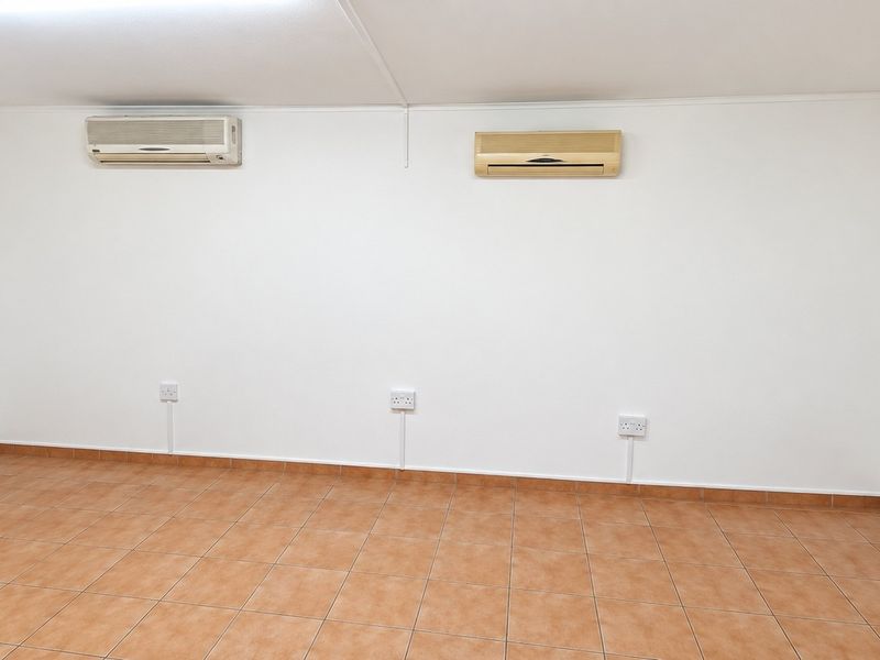 A vacant office space featuring ceramic tiled flooring, multiple electrical outlets, and two wall-mounted air conditioning units.