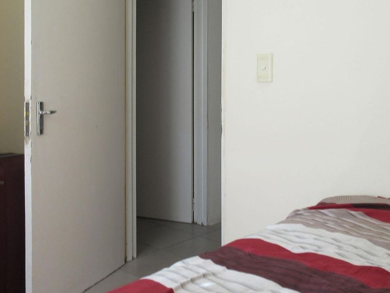 A view of a bedroom interior showing a doorway leading to a hallway and a light switch on the wall.