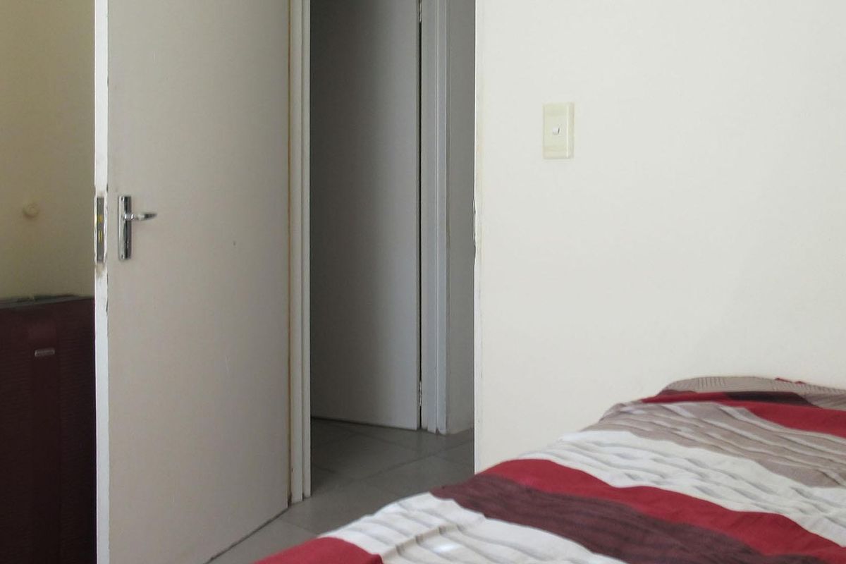 A view of a bedroom interior showing a doorway leading to a hallway and a light switch on the wall.